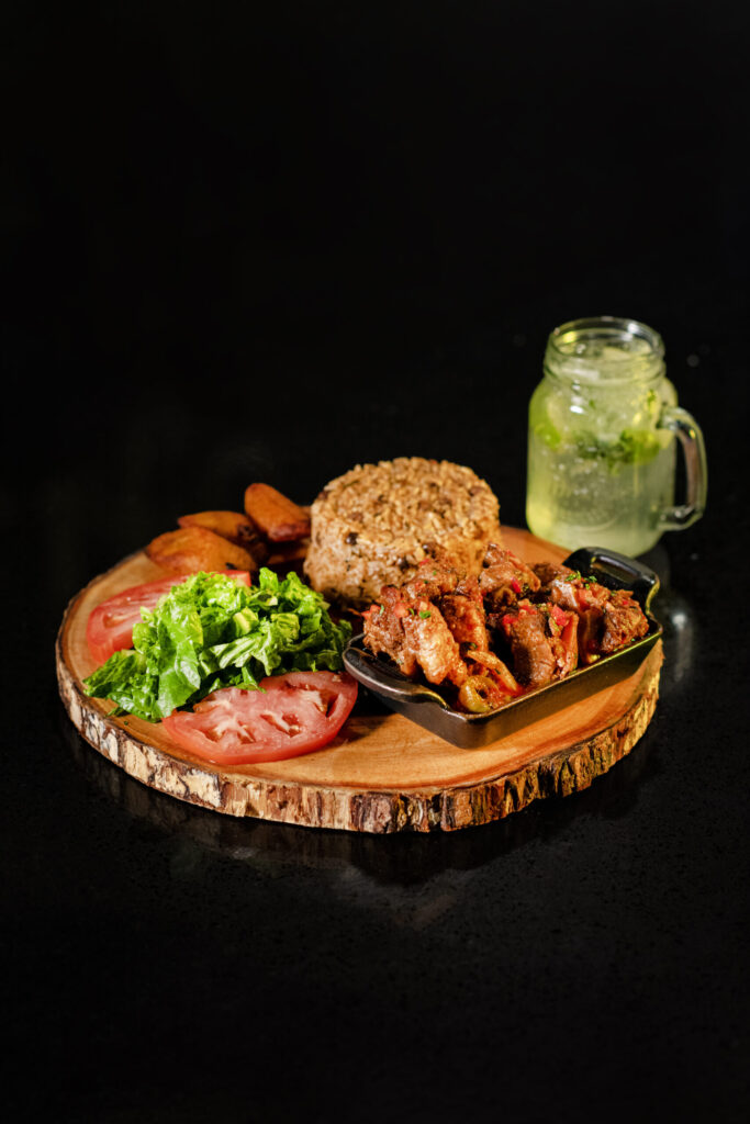 Plato dominicano con moro, carne y ensalada sobre tabla de madera